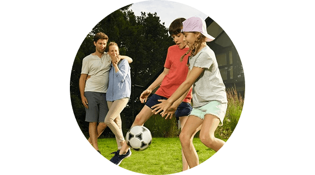 Familie mit privater Haftpflichtversicherung spielt Fußball im Garten.