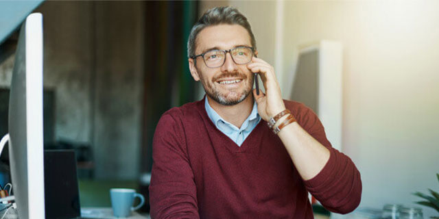 Ein Mann im roten Pullover telefoniert mit seinem VGH - Berater. 