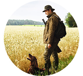 Jäger steht mit Hund am Feldrand