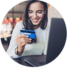 Frau sitzt mit Kreditkarte am Computer und jagt nach Online-Schnäppchen