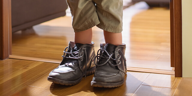 Symbolbild Kind mit zu großen Schuhen