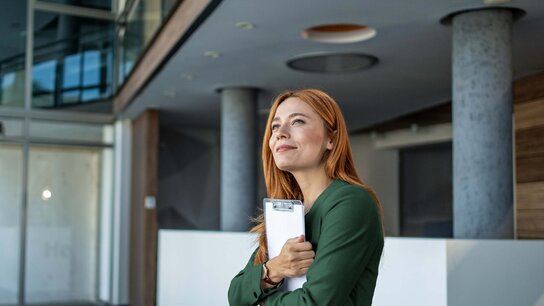 Zwei Männer im Geschäftsanzug sitzen in einem modern eingerichteten Büro und besprechen Dokumente. Sie lachen und sind freundlich.