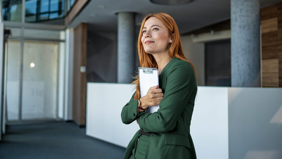 Zwei Männer im Geschäftsanzug sitzen in einem modern eingerichteten Büro und besprechen Dokumente. Sie lachen und sind freundlich.