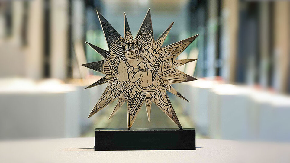 Dreidimensionaler Stern mit detaillierten Gravuren, der eine Szene mit einer Figur und Häusern darstellt.